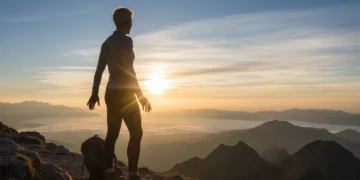 Determined person on mountain path at sunrise, symbolizing self-discipline and new beginnings
